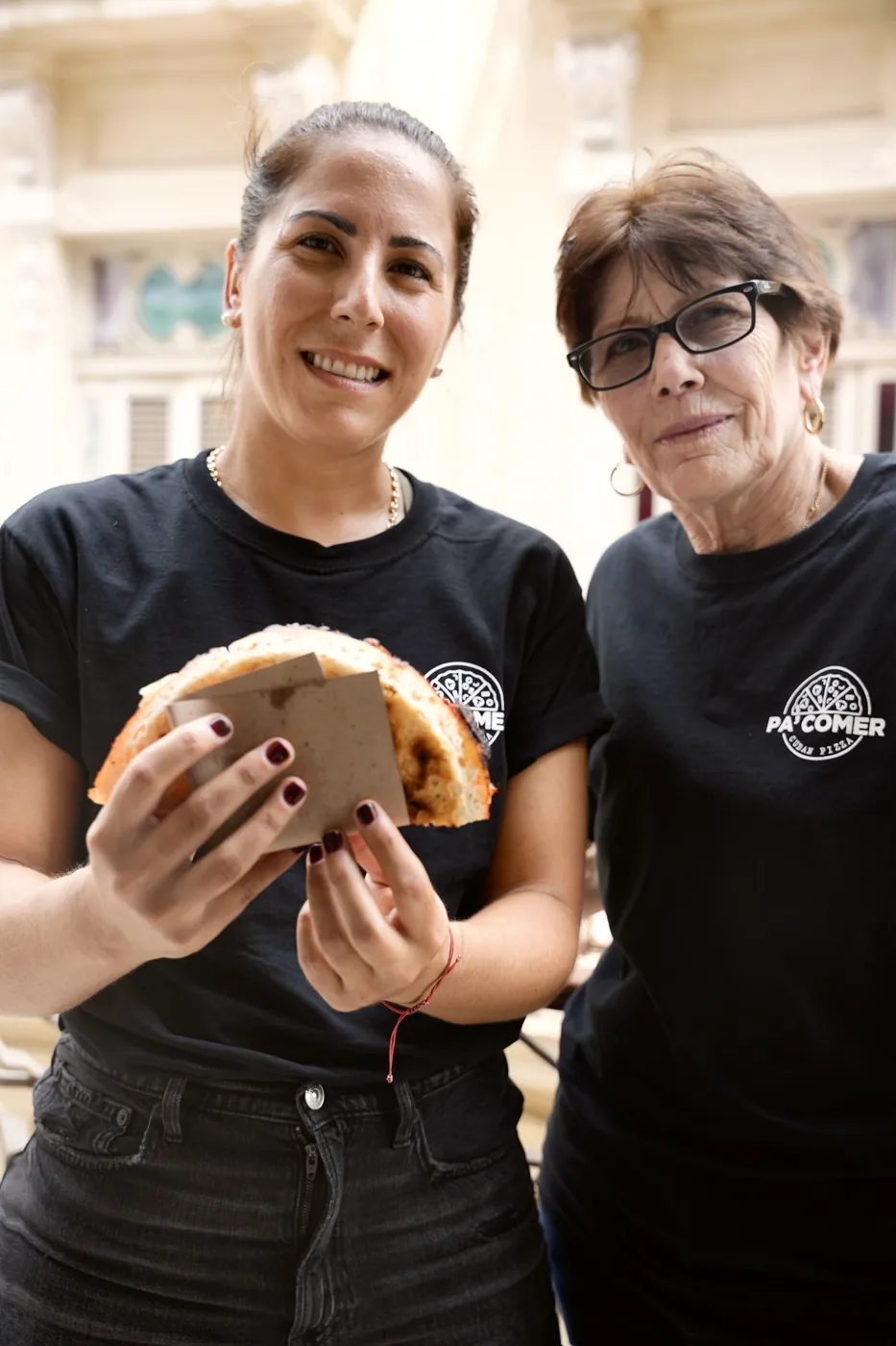 Elizabeth and her mother Gina in Cuba, wearing Pa’ Comer shirts and holding a slice of pizza