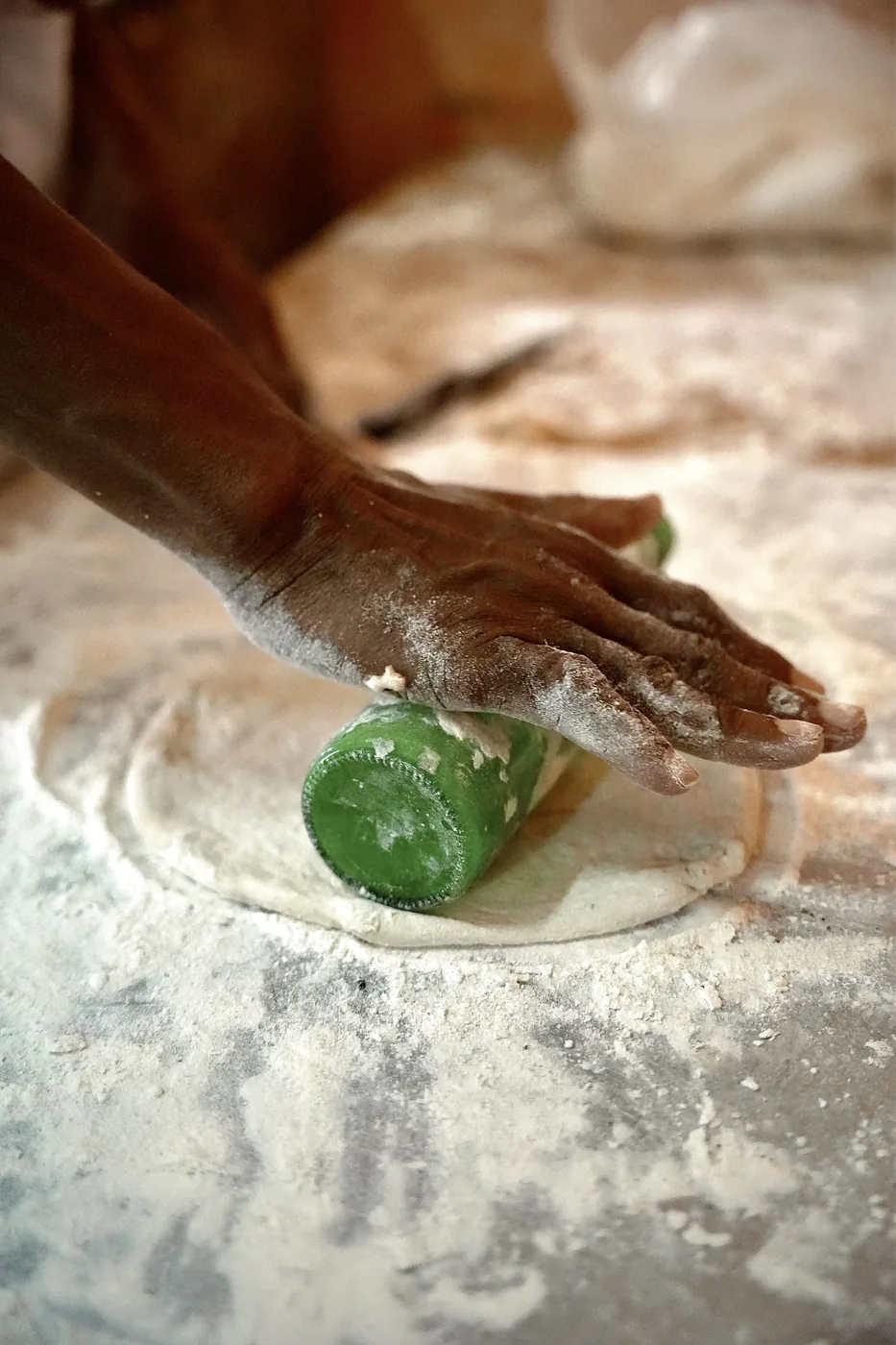 Hands rolling out dough on a stone counter
