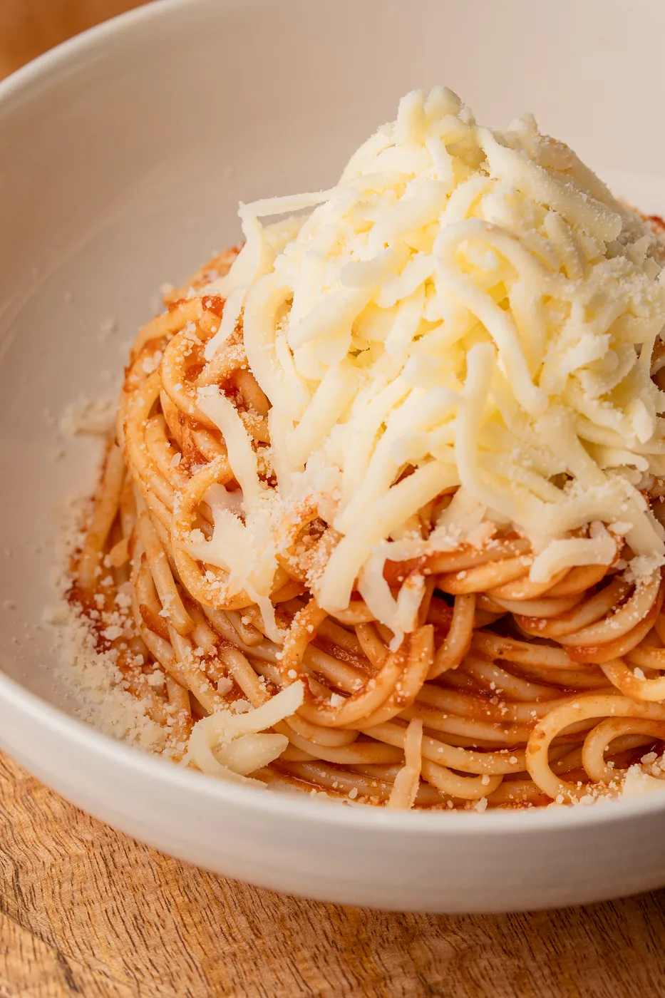 Neapolitan spaghetti topped with a mountain of shredded cheese