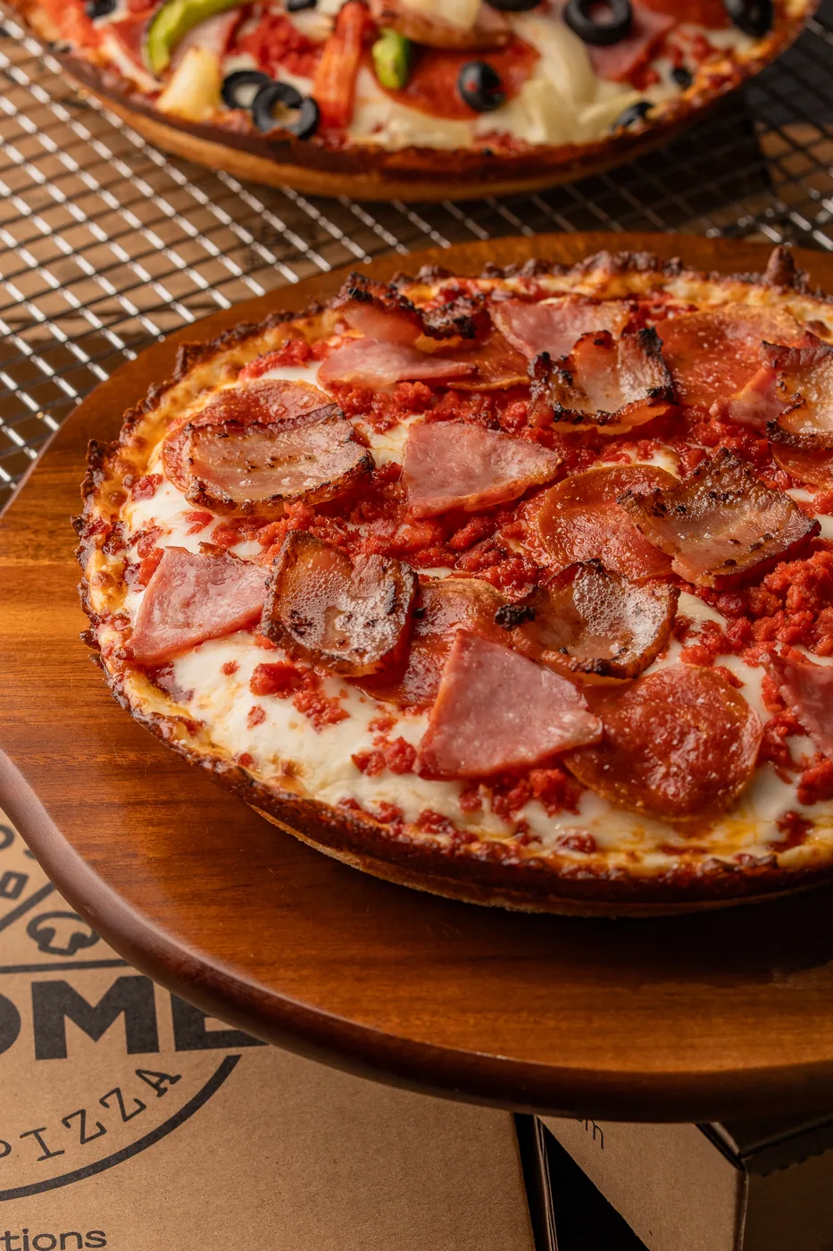 PA’ COMER’s meat lover pizza on a wooden board, fresh from the oven