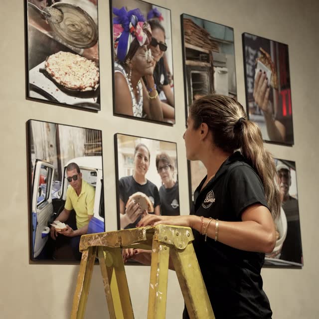 Elizabeth on a ladder, hanging the photos from the Cuba trip on the shop wall