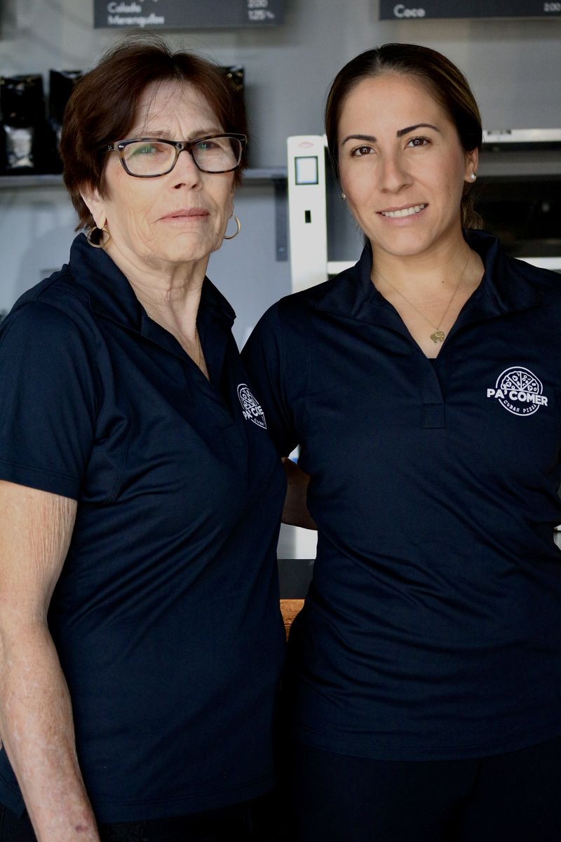 Gina and her daughter Elizabeth, founders of Pa’ Comer, at the shop wearing the brand polo